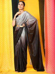 Woman wearing a black and gray saree with a gold belt against a colorful background
