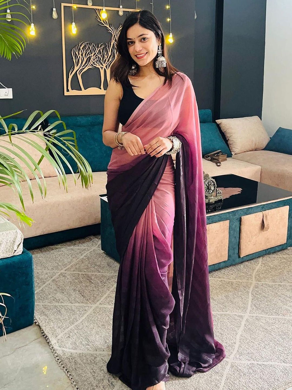 Woman wearing a pink and purple saree in a living room setting
