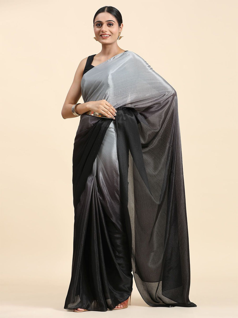 Woman wearing a black and gray saree on a beige background