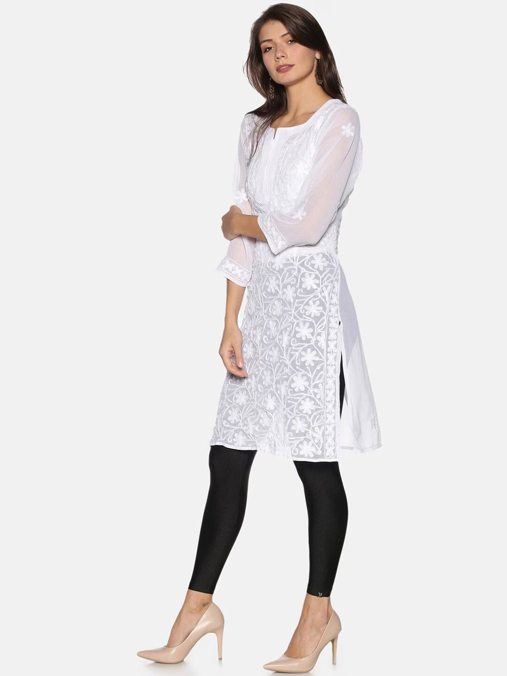 Woman wearing a white lace dress with black leggings on a white background